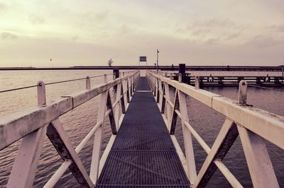 Pier on sea against cloudy sky