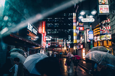 People on illuminated street amidst buildings in city at night