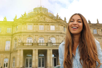 Smiling cheerful young woman in front of neues schloss of stuttgart, germany.