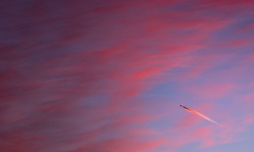 Low angle view of vapor trails against sky during sunset