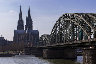 Bridge over river in city against sky