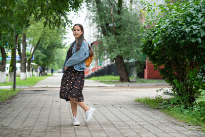 Portrait of young woman standing on footpath