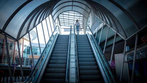 Low angle view of mid adult woman standing on escalator