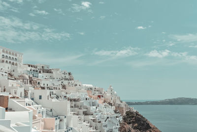 Buildings by sea against sky