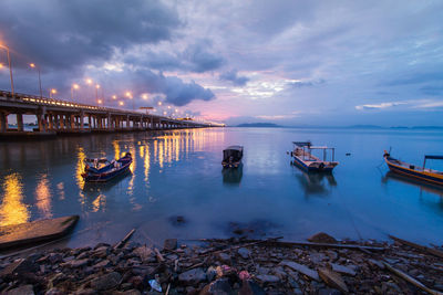 Boats moored on sea against sky during sunset