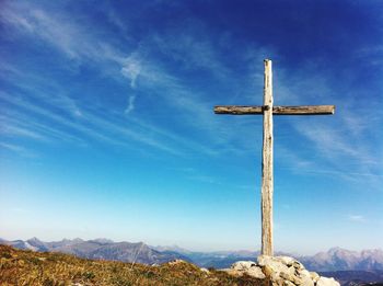 Low angle view of cross on mountain against blue sky