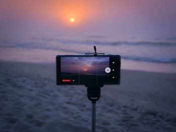 Information sign on beach against sky during sunset