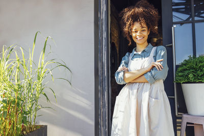 Portrait of young woman standing against window