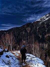 Rear view of man standing on snow against sky