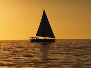 Sailboat sailing on sea against sky during sunset