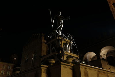 Low angle view of illuminated statue against building at night