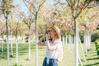 Close-up of woman photographing while standing against trees