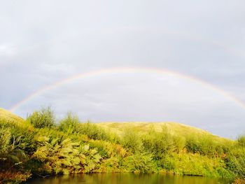 Scenic view of rainbow over lake against sky