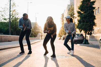 Teenage girl dancing with male friends on street in city