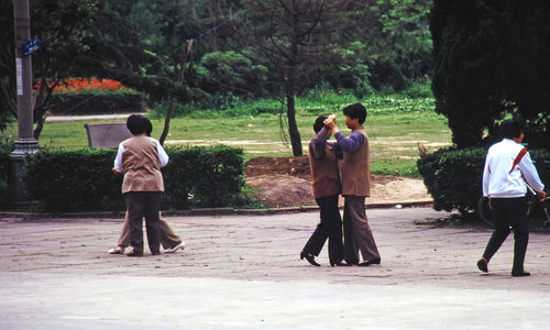 Rear view of people standing against trees