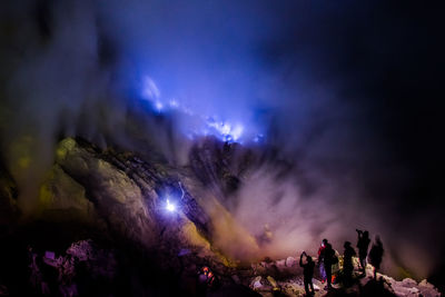 People on standing on mountain against sky at night