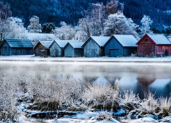 Houses by lake against buildings during winter