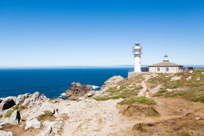 Lighthouse by sea against sky