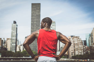 Rear view of man standing against modern buildings in city