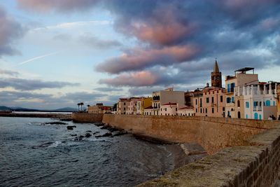 Buildings by sea against sky in city