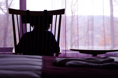 Rear view of woman sitting on chair at home