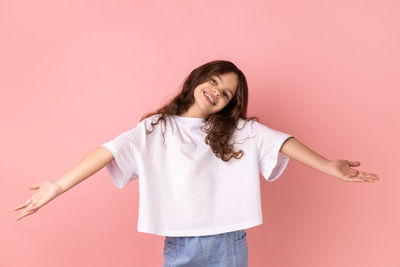 Young woman standing against pink background