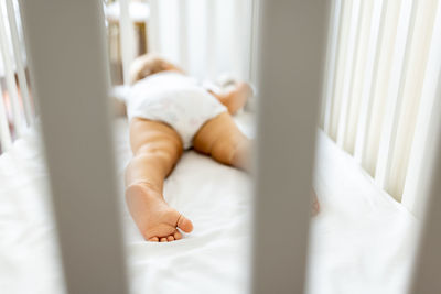 Low section of baby sleeping on bed at home