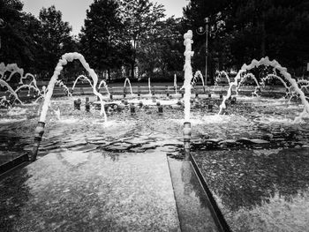 Fountain in park by lake against sky