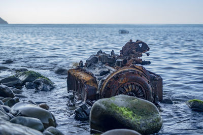 Old rusty engine lying among stones in the water.