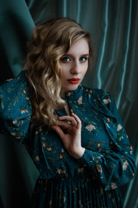 Mysterious portrait of a young blonde girl on a blue background face close-up