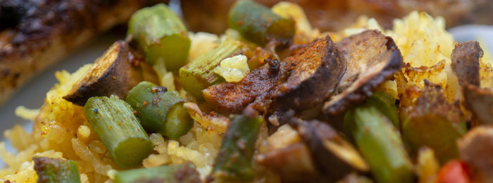 Fried hot mushrooms and pieces of green asparagus on yellow curry rice, eat