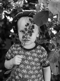 Portrait of boy holding twig against plants