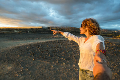 Smiling mature woman gesturing while holding hands during sunset