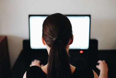 Rear view of woman working on computer at office