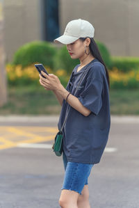 Woman using smart phone on footpath