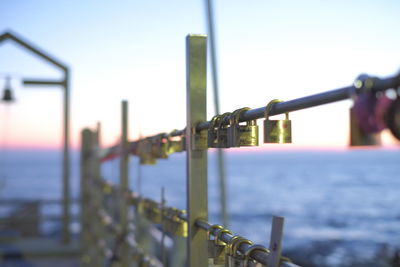 Metal railing by sea against clear sky