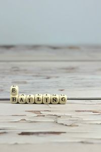 Close-up of text on table at beach against sky