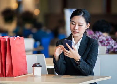 Mid adult woman using mobile phone at table