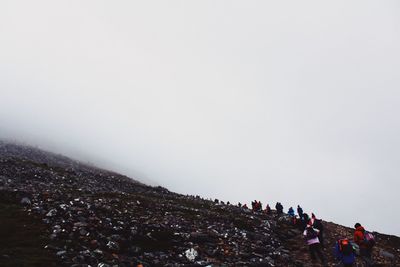 People on mountain against clear sky