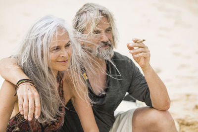 Portrait of senior hippie couple smoking on the beach