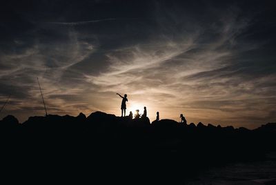 Silhouette people standing against sky during sunset