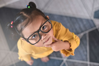 Smart little asian girl with thinking gesture looking at camera.