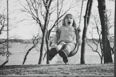 Girl in swing against sky
