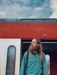 Portrait of young man standing against red car