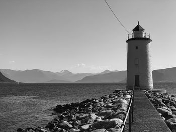 Lighthouse by sea against sky