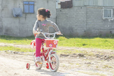 Full length of woman with bicycle against brick wall