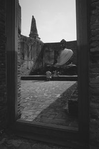 People sitting at temple against sky