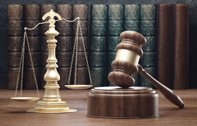 Close-up of wooden gavel by weight scale and books on table