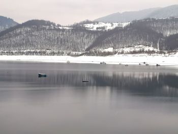 Scenic view of lake by snowcapped mountains against sky