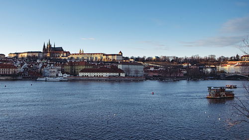 Scenic view of river by cityscape against sky